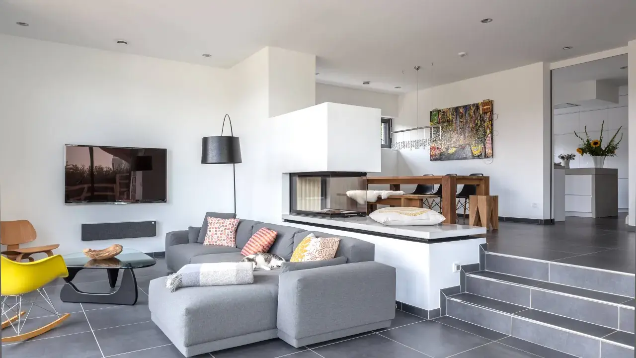 Modernes Split-Level-Haus mit offenem Wohnbereich, Kamin, Essbereich und Küche. Ein Kater döst auf dem Sofa.