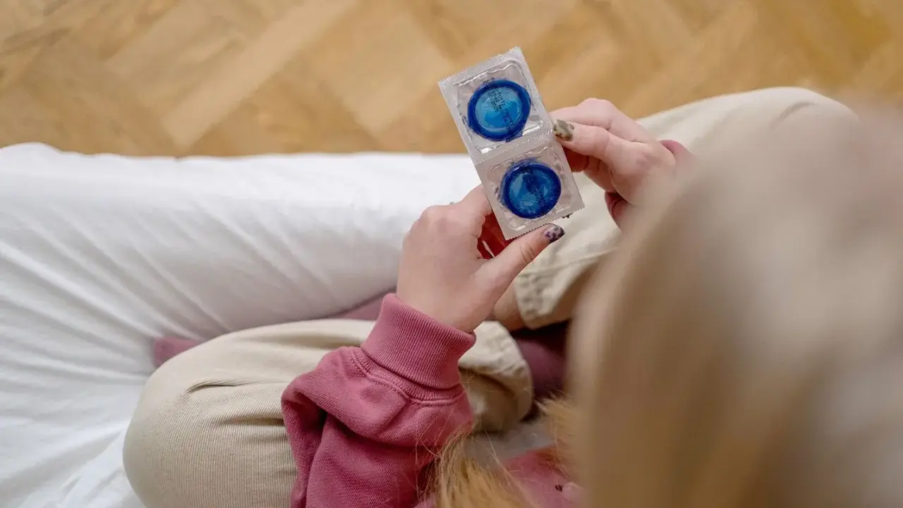 Dłonie trzymają opakowanie z dwoma prezerwatywami. To ważny element, gdy zastanawiasz się, co to antykoncepcja.