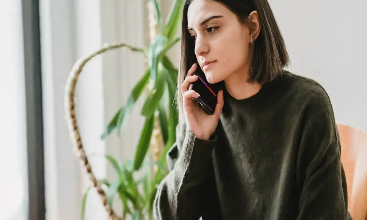 Zmartwiona kobieta rozmawia przez telefon, zastanawiając się, czy pracodawca może cofnąć urlop.