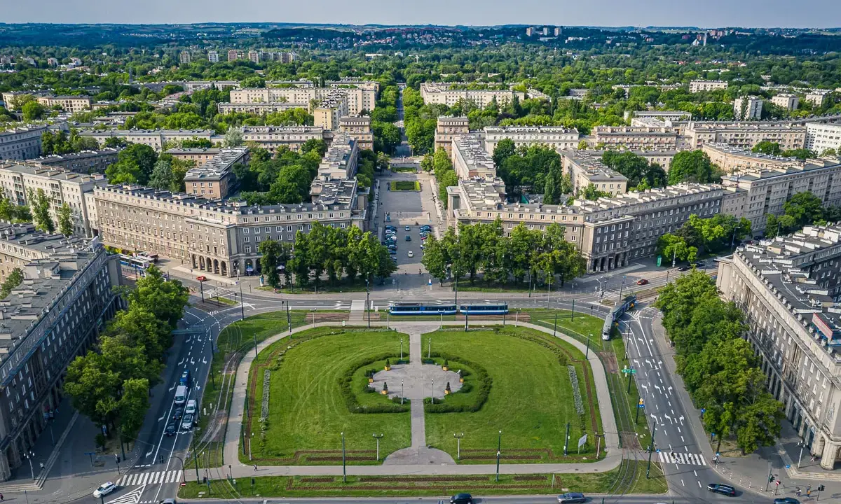 Plac Centralny w Nowej Hucie z socrealistyczną zabudową, zielonymi skwerami i torami tramwajowymi.