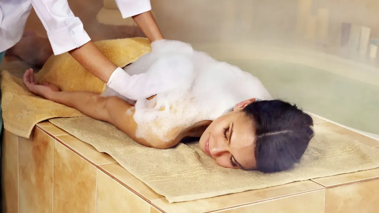 Eine Frau genießt eine Schaummassage im Hamam. Die Bedeutung von Hamam liegt in der tiefen Entspannung und Reinigung.