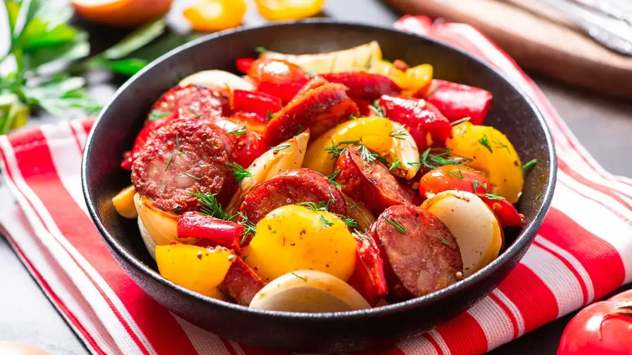 Salsiccia e patate in padella, un piatto saporito con peperoni rossi e gialli, cipolle e erbe aromatiche fresche.