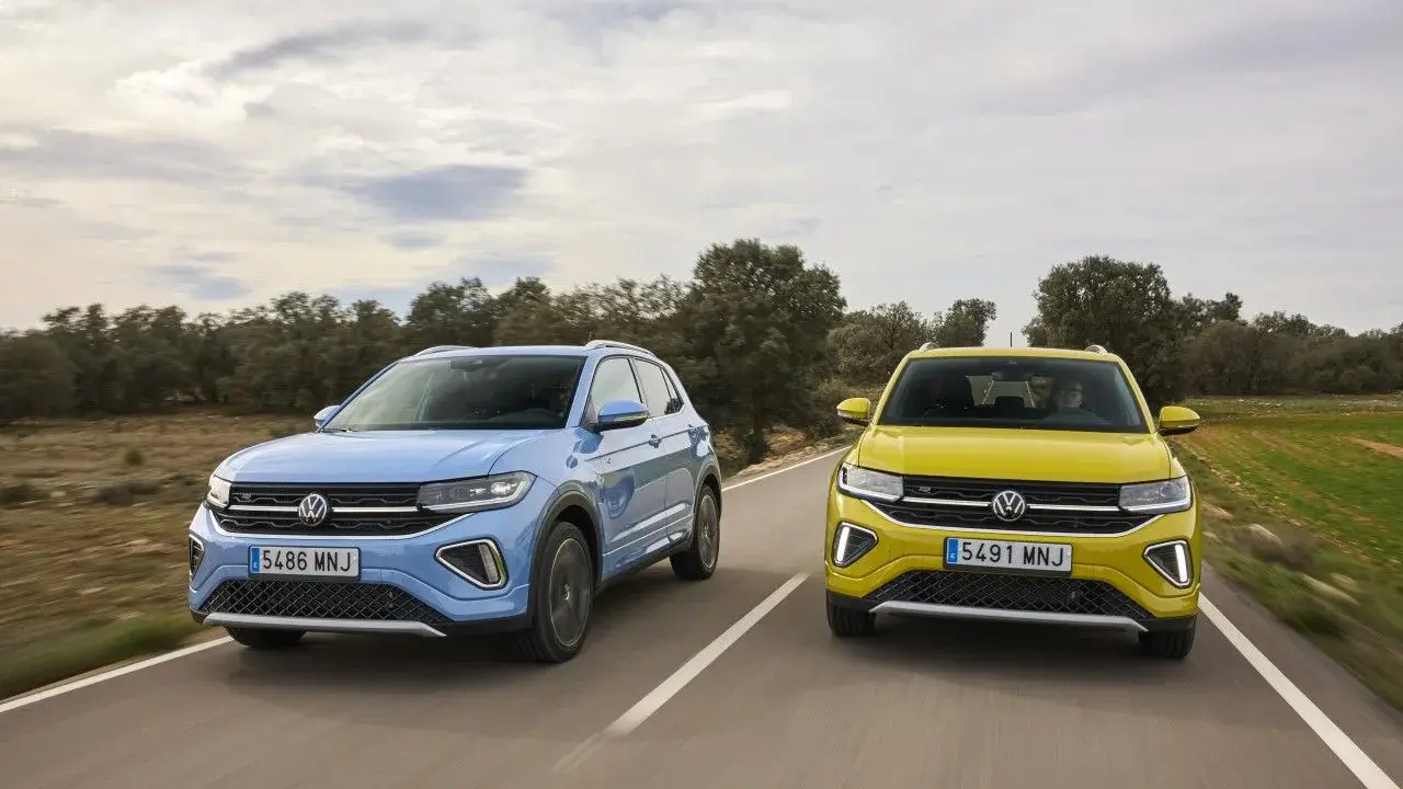 Un Volkswagen T-Cross azul y un T-Roc amarillo circulan por una carretera rural.