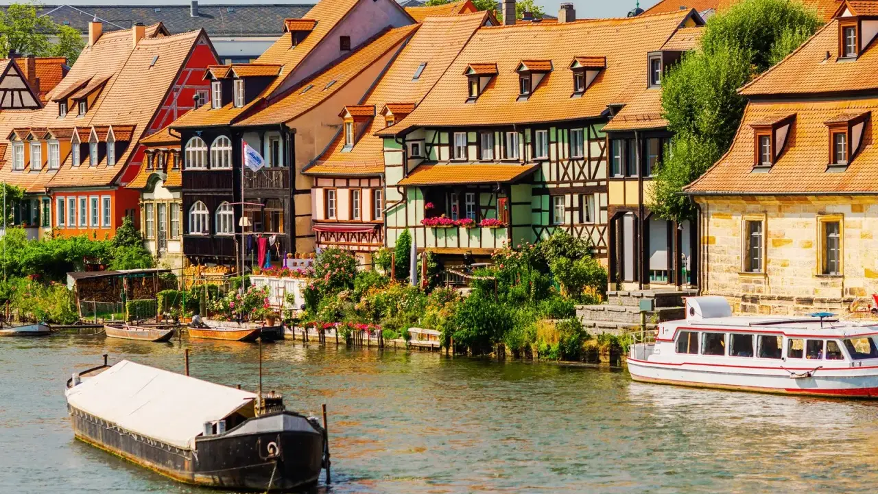 Bunte Fachwerkhäuser säumen das Wasser, Boote schaukeln sanft. Ein malerischer Anblick, der die vielen Attraktionen Bayerns widerspiegelt.