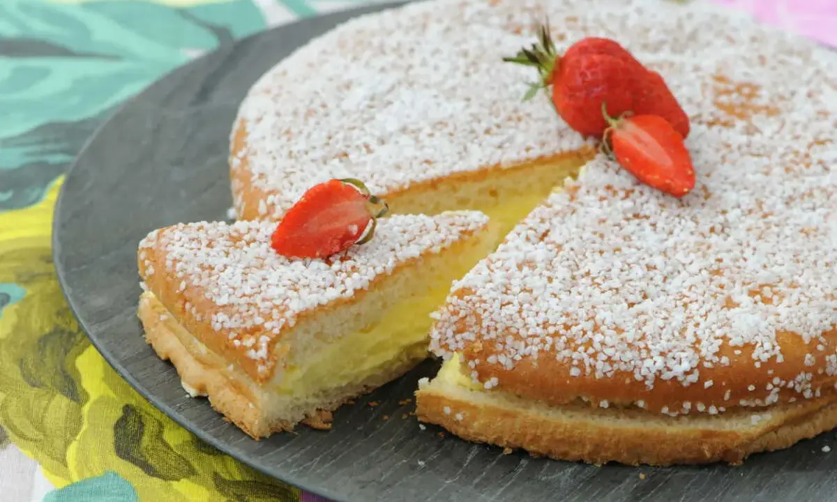 Un délicieux gâteau génoise crème pâtissière, saupoudré de sucre et garni de fraises fraîches.