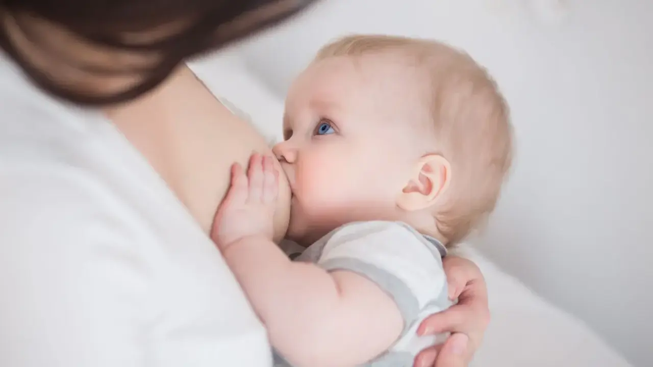Niebieskooki niemowlak karmiony piersią. Czasem pojawia się kryzys laktacyjny, ale to naturalny etap.