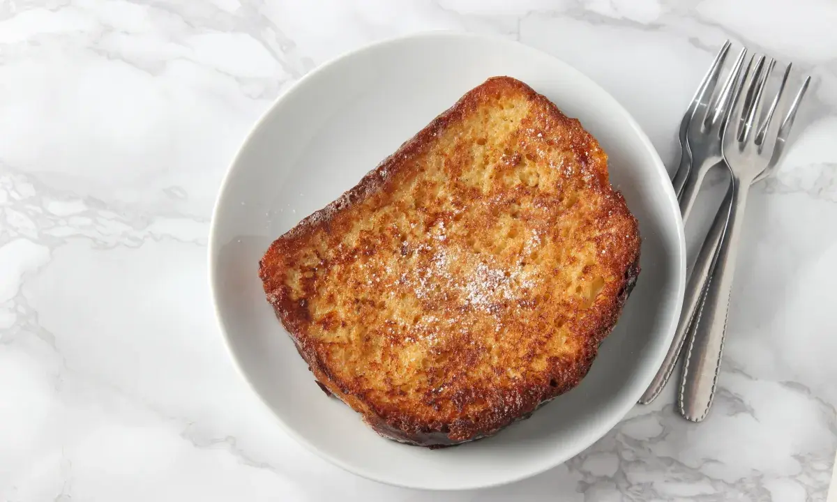 Tostada francesa dorada, espolvoreada con azúcar glas. Perfecta para tu próxima french toast receta.