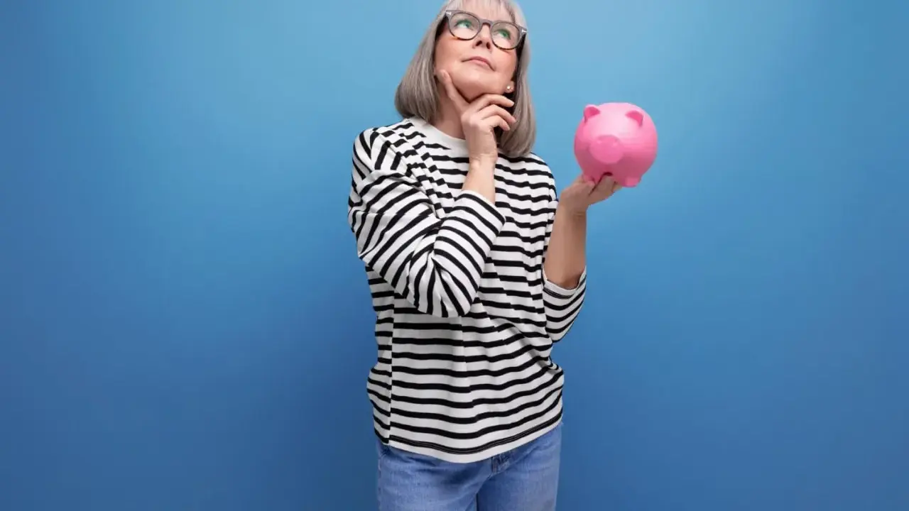 Mujer pensativa con hucha rosa, considerando los tipos de planes de pensiones para su futuro.