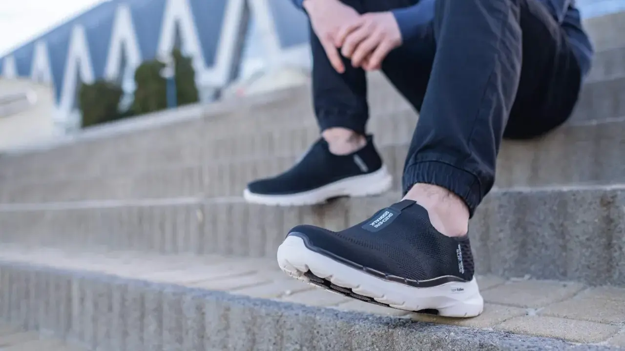 Czarne, wsuwane buty sportowe na białej podeszwie, idealne jako buty dla seniorów, zapewniające komfort i stabilność na schodach.