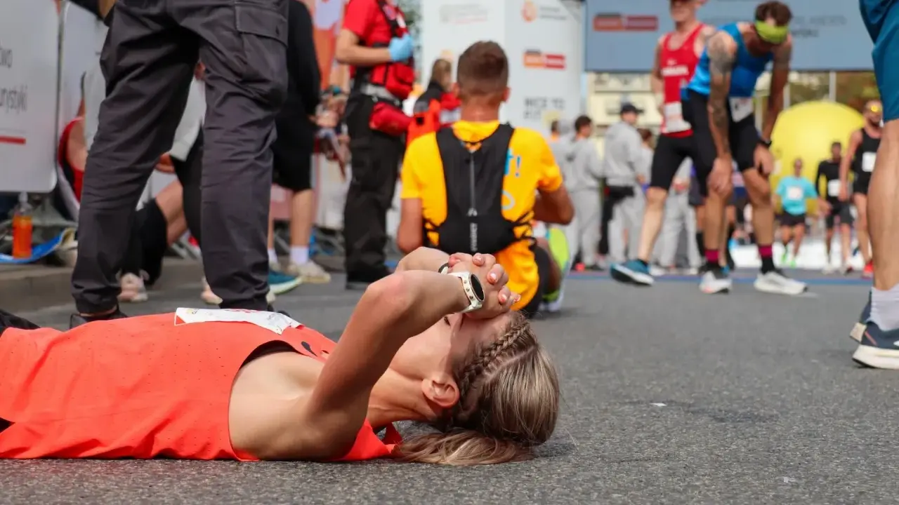 Zmęczona biegaczka leży na ziemi po tym, jak dowiedziała się, ile biegnie się maraton.