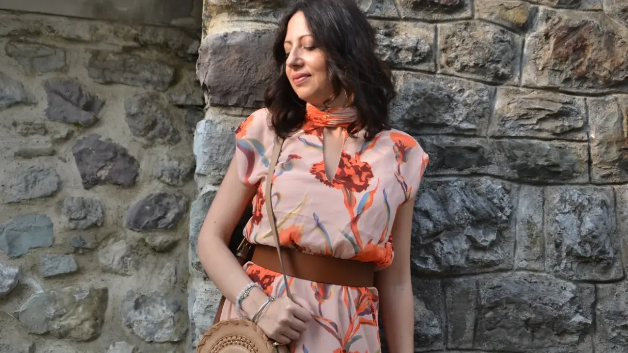 Donna con abito floreale rosa antico, cinturone marrone e borsa rotonda. I colori vivaci del vestito sono perfetti per abbinare al rosa antico.