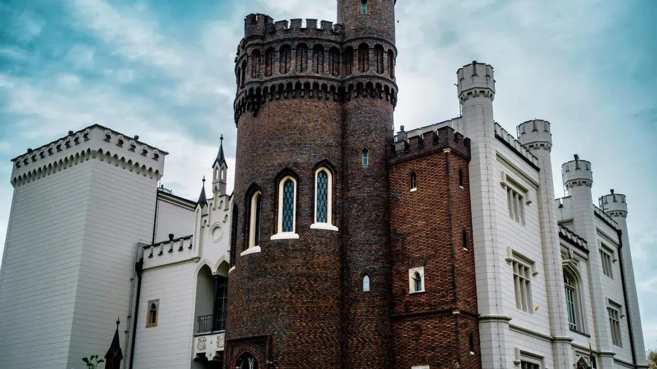 Zamek w Kórniku, jedna z najpiękniejszych atrakcji okolic Poznania, z ceglaną wieżą i białymi skrzydłami.