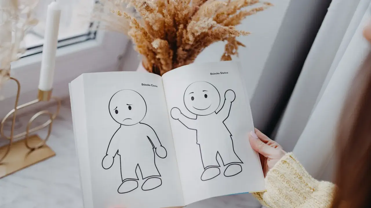 Otwarta książka pokazuje rysunki smutnego i radosnego dziecka, symbolizujące nasze wewnętrzne dziecko.