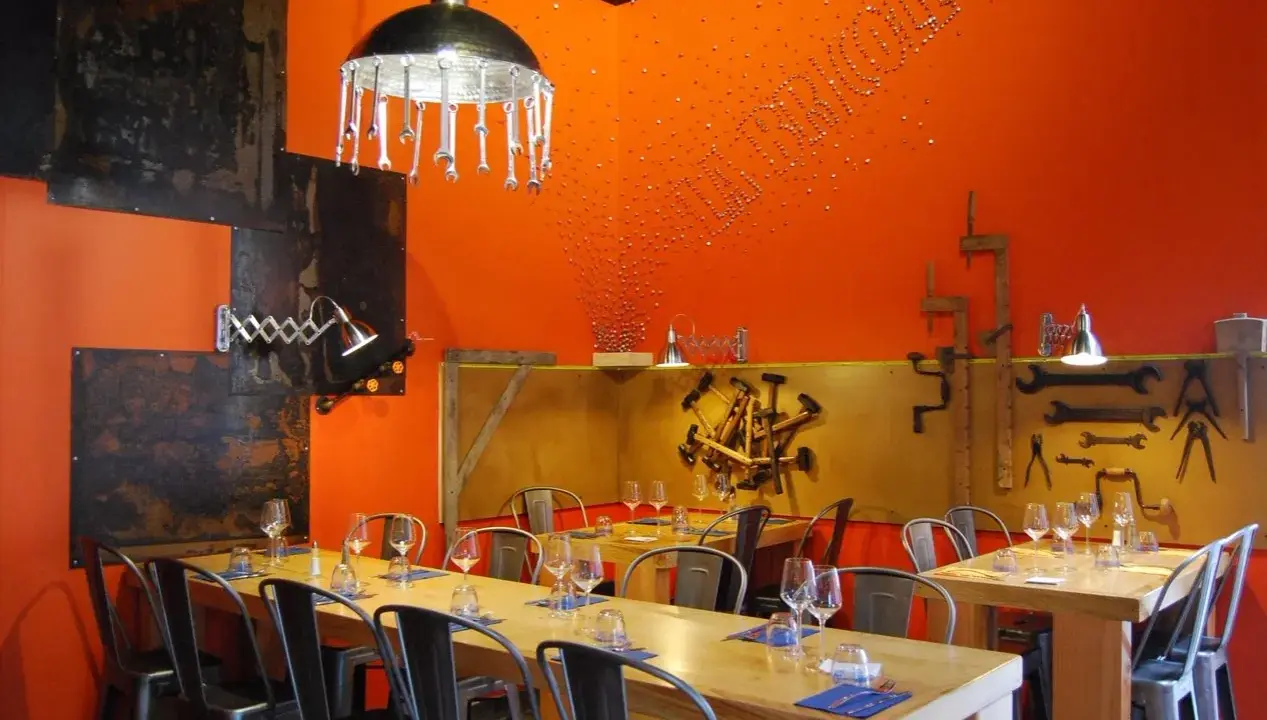 Ambiance industrielle dans un des restaurants de Chambray-lès-Tours. Tables dressées, murs orange vif, luminaires originaux.