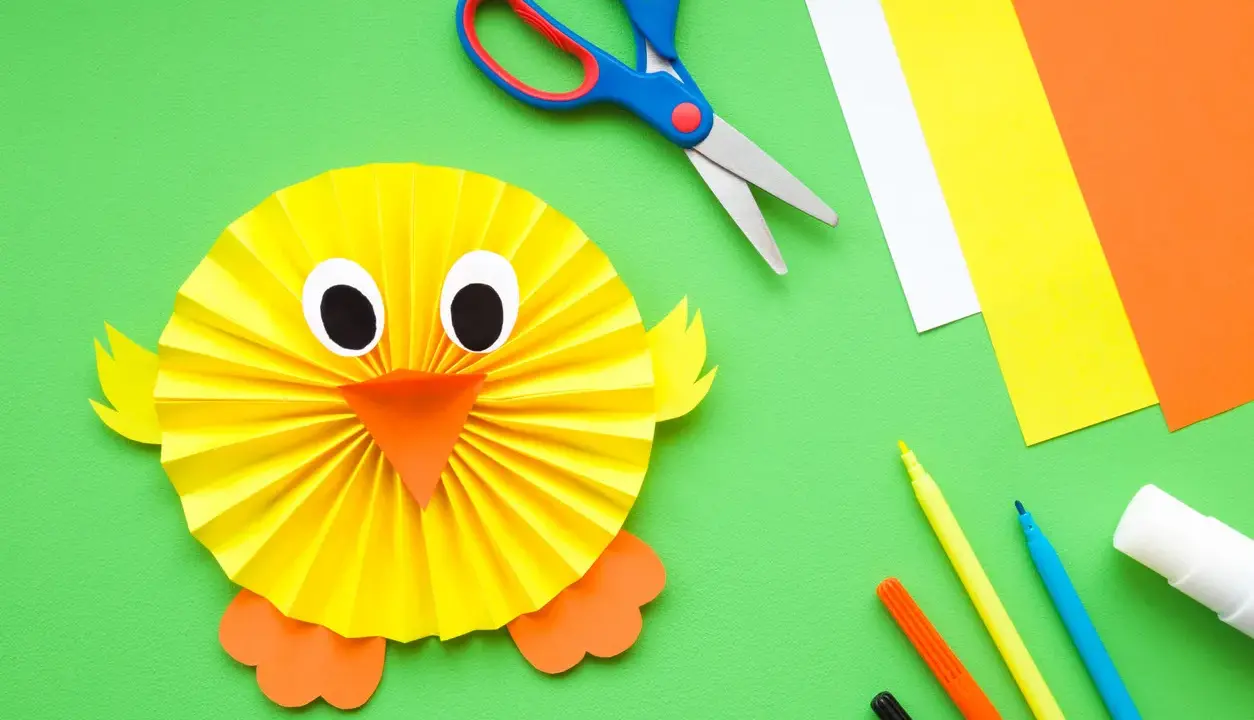 Manualidades para niña de 2 años: un pollito de papel. Tijeras, papeles de colores, rotuladores y pegamento listos para crear.