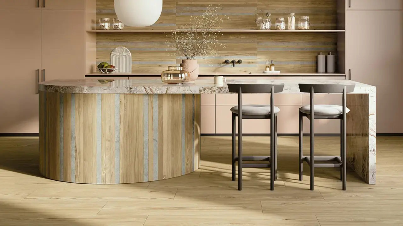 Interni di una casa super moderna: isola cucina in legno e marmo, sgabelli grigi, mobili rosa cipria e pavimento in parquet chiaro.