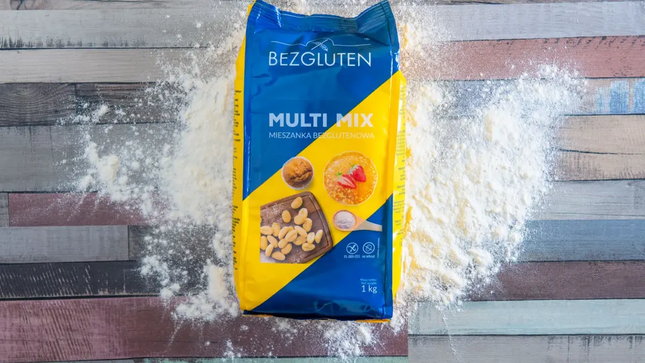 Opakowanie mąki bez glutenu "Multi Mix" rozsypane na drewnianym blacie. Idealna do wypieków dla osób na diecie bezglutenowej.