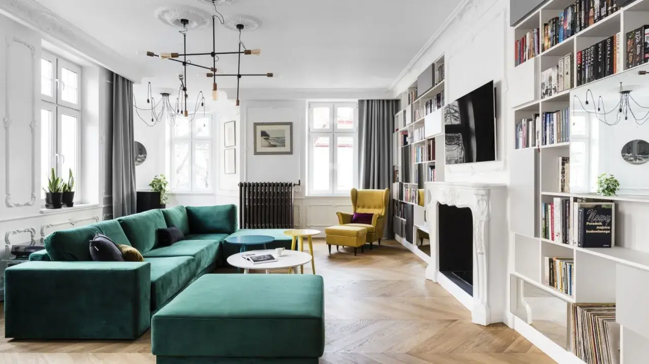 Elegancki salon w stylu paryskim z zieloną kanapą, żółtym fotelem i regałami pełnymi książek.