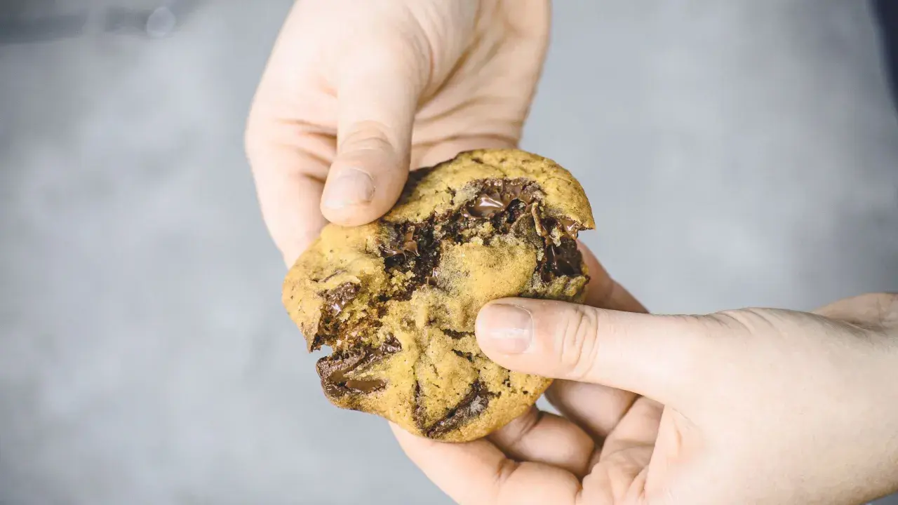 Hände halten einen frisch gebackenen Chocolate Chip Cookie, der nach einem einfachen Cookies Rezept gemacht wurde.