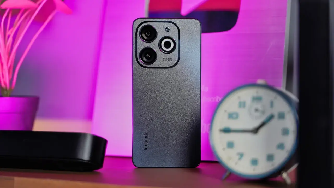 Szary smartfon Infinix z potrójnym aparatem na tle różowego światła. Czy to Infinix co to za firma?