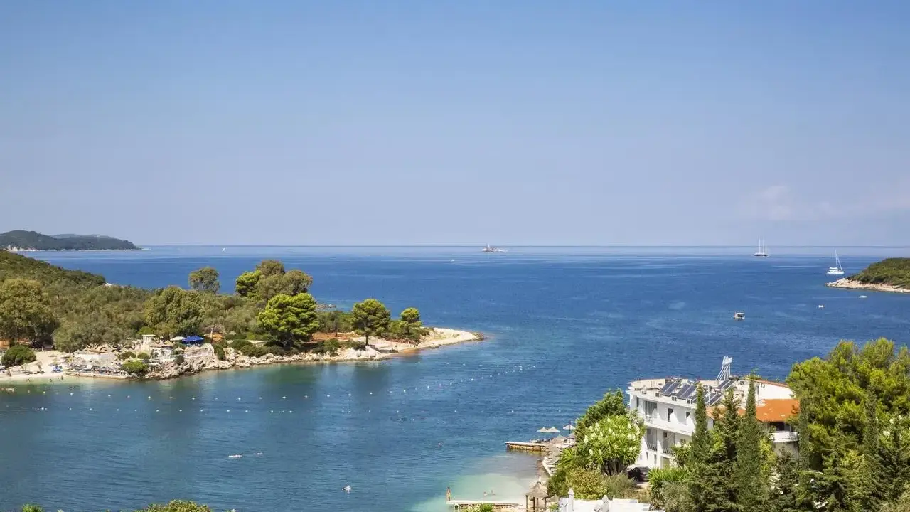 Piękna zatoka w Ksamil, Albania, z turkusową wodą, zielonymi wyspami i białym hotelem. Idealne miejsce na wakacje.