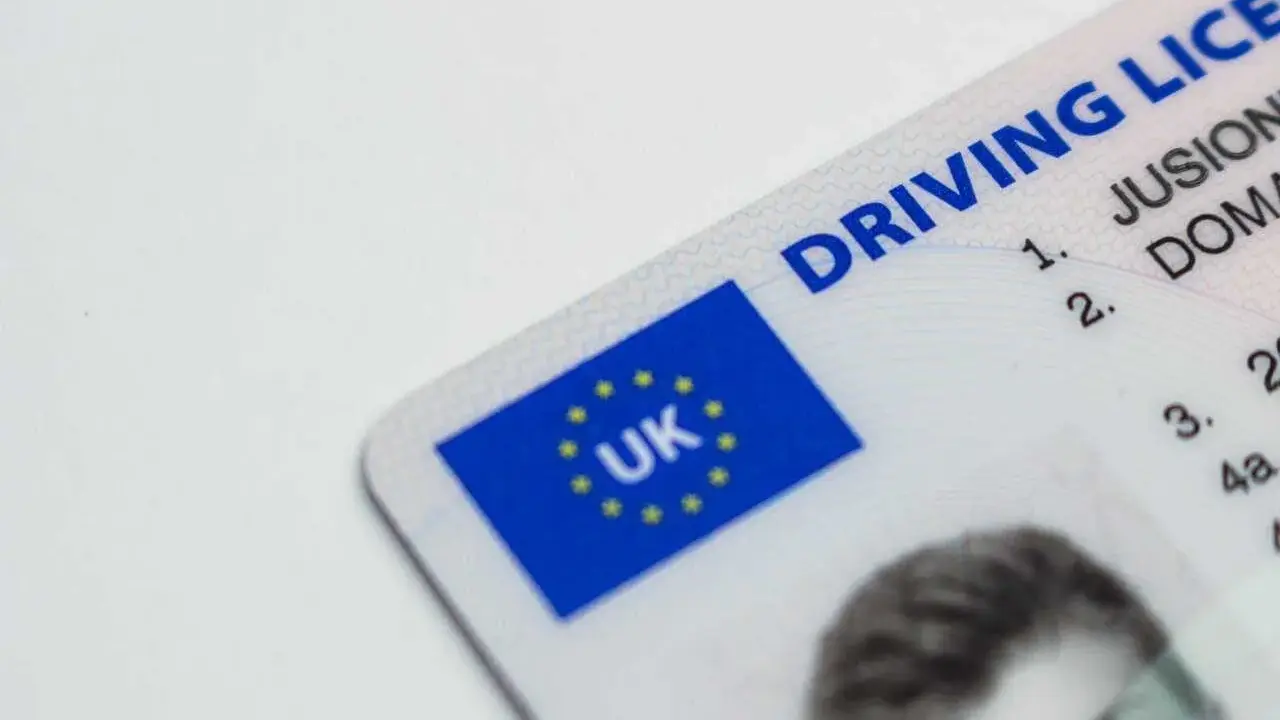 Brytyjskie prawo jazdy. Czy można jeździć oczekując na wymianę prawo jazdy? Dokument z flagą UK.