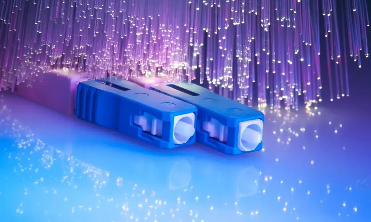 Connecteurs bleus pour télécommunication fibre optique, entourés de fils lumineux violets.