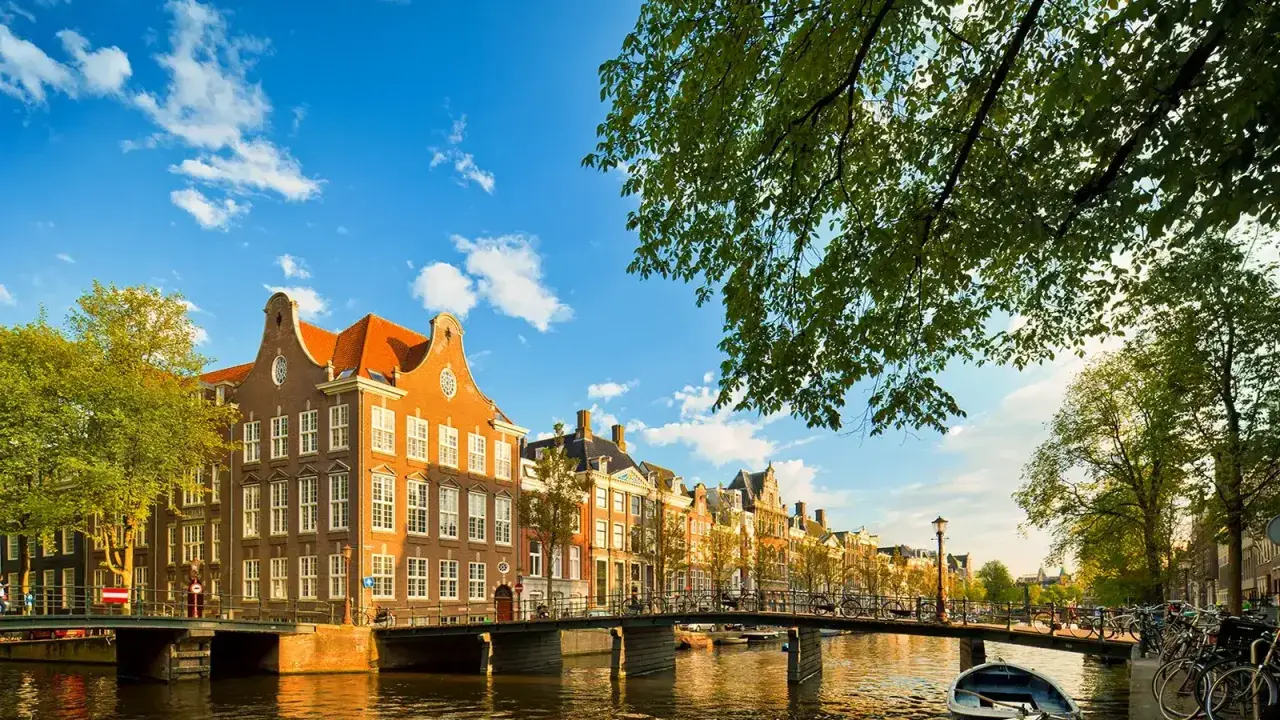 Un paseo por los canales de Amsterdam con adolescentes, disfrutando de las casas históricas y el sol.