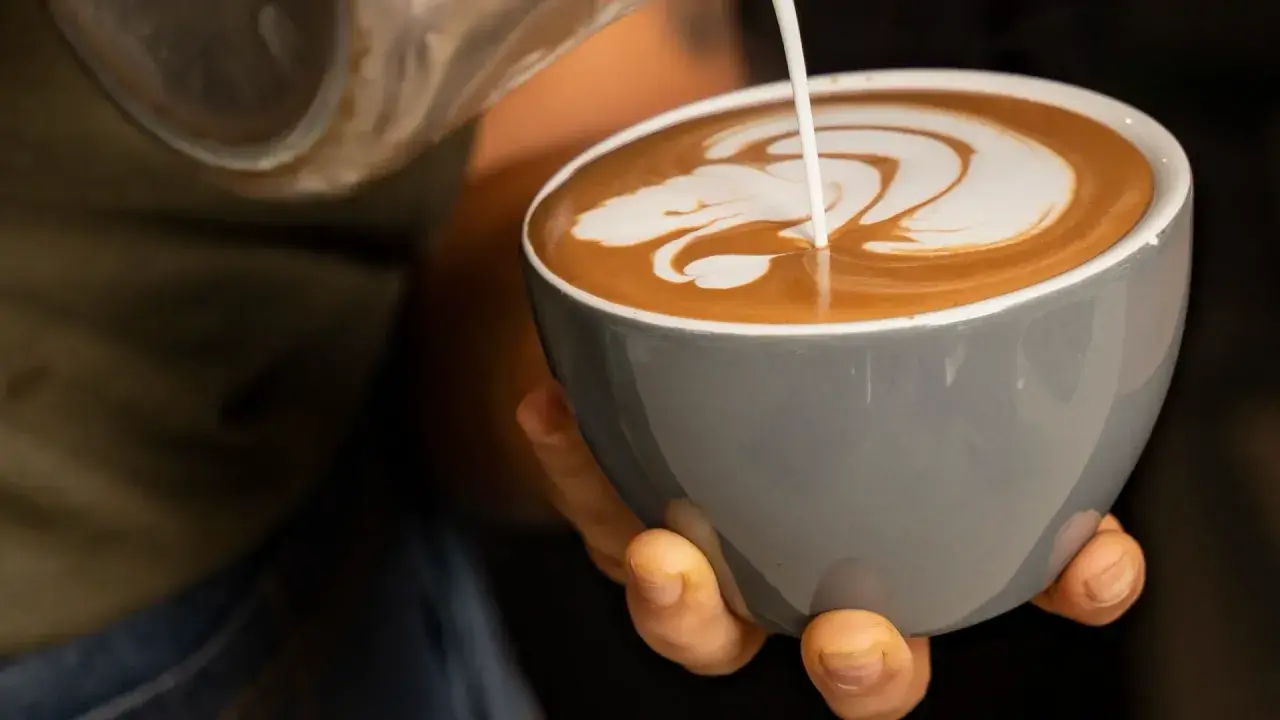 Barista verziert einen Espresso Latte mit Milchschaum. Ein Kunstwerk in der Tasse.