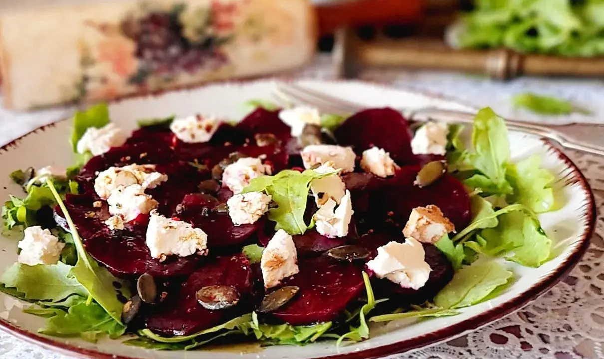Pyszne carpaccio z buraka z serem feta, rukolą i pestkami dyni na talerzu.