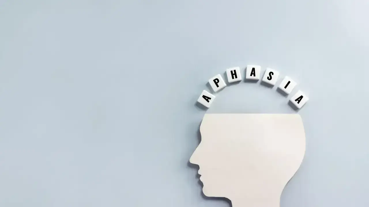 Biały profil głowy z literami tworzącymi łuk nad nią. Litery układają się w słowo "APHASIA", symbolizując afazję motoryczną.