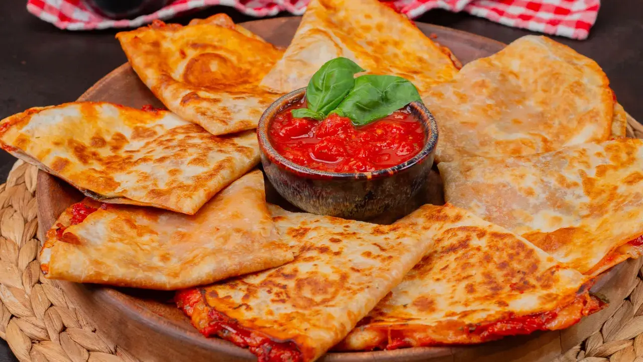 Goldbraune Quesadillas, gefüllt mit geschmolzenem Käse und Tomaten, serviert mit frischem Basilikum. Ein einfaches Quesadillas Rezept für jeden Anlass.