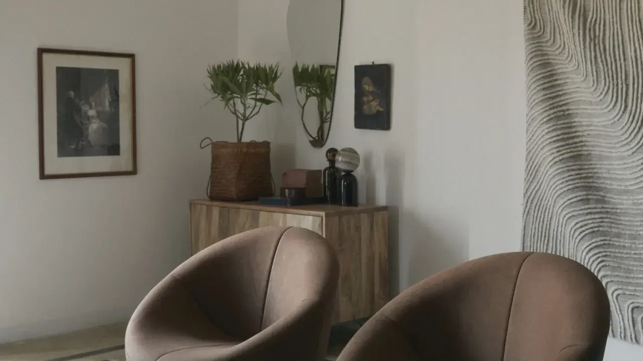Två bruna fåtöljer framför en träbyrå med spegel och konst. En inredningsdröm inspirerad av Marie Olsson Nylander för Ellos.