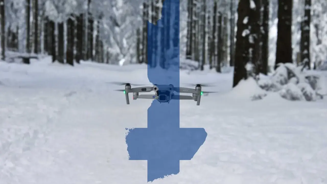 Eine Drohne fliegt über eine verschneite finnische Landschaft. Die Silhouette Finnlands ist über das Bild gelegt.
