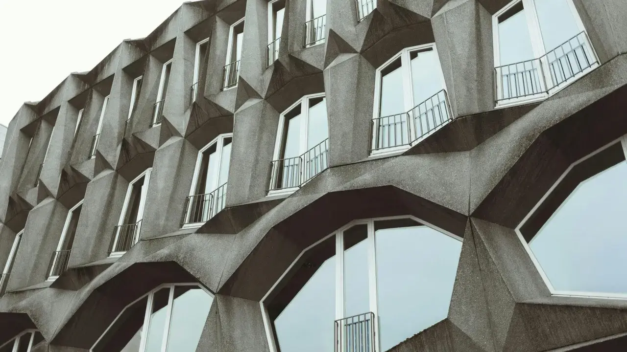 Fassade eines Gebäudes im Stil der brutalismus architektur mit geometrischen Betonformen und vielen Fenstern.