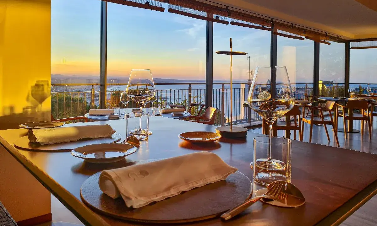 Tavola apparecchiata in un ristorante stellato a Gabicce Monte, con vista sul tramonto sul mare.