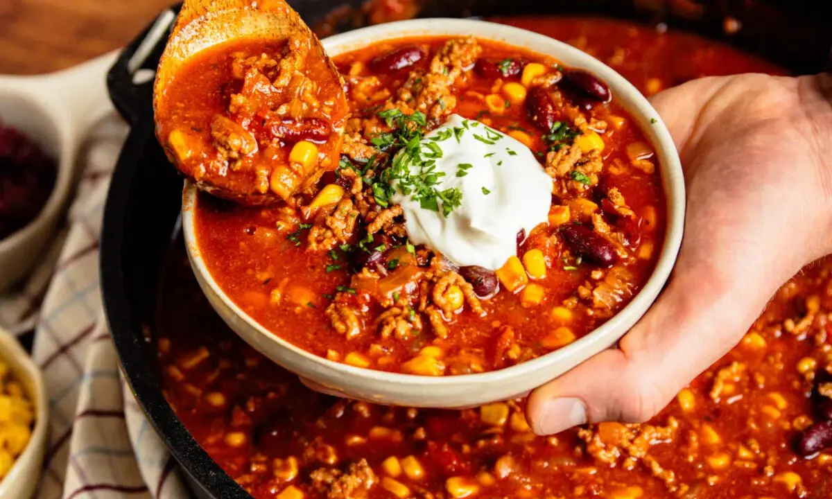Herzhaftes Chili con Carne aus dem Dutch Oven, serviert mit einem Klecks Sour Cream und frischer Petersilie.