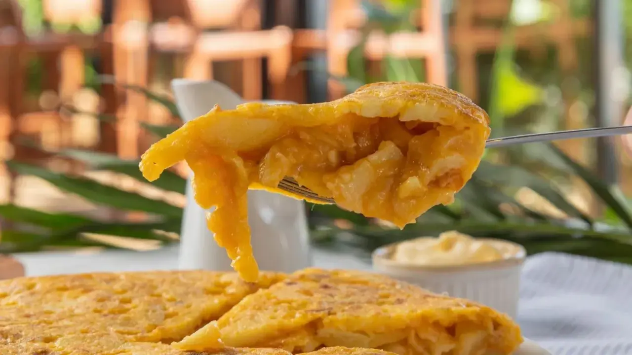 Un tenedor levanta un trozo jugoso de tortilla de espaguetis, mostrando su interior dorado y tierno.