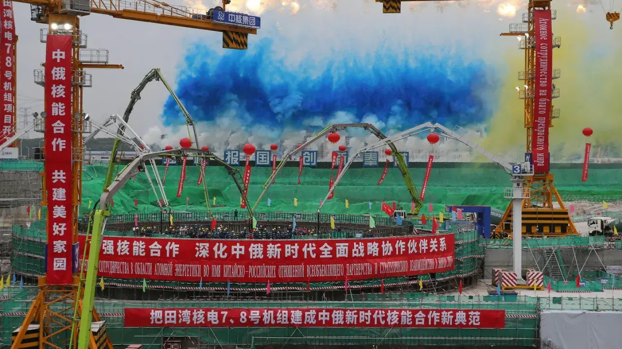 Bau von China Atomkraft-Anlagen mit Kränen und bunten Rauchsäulen. Chinesische und russische Banner feiern die Zusammenarbeit.