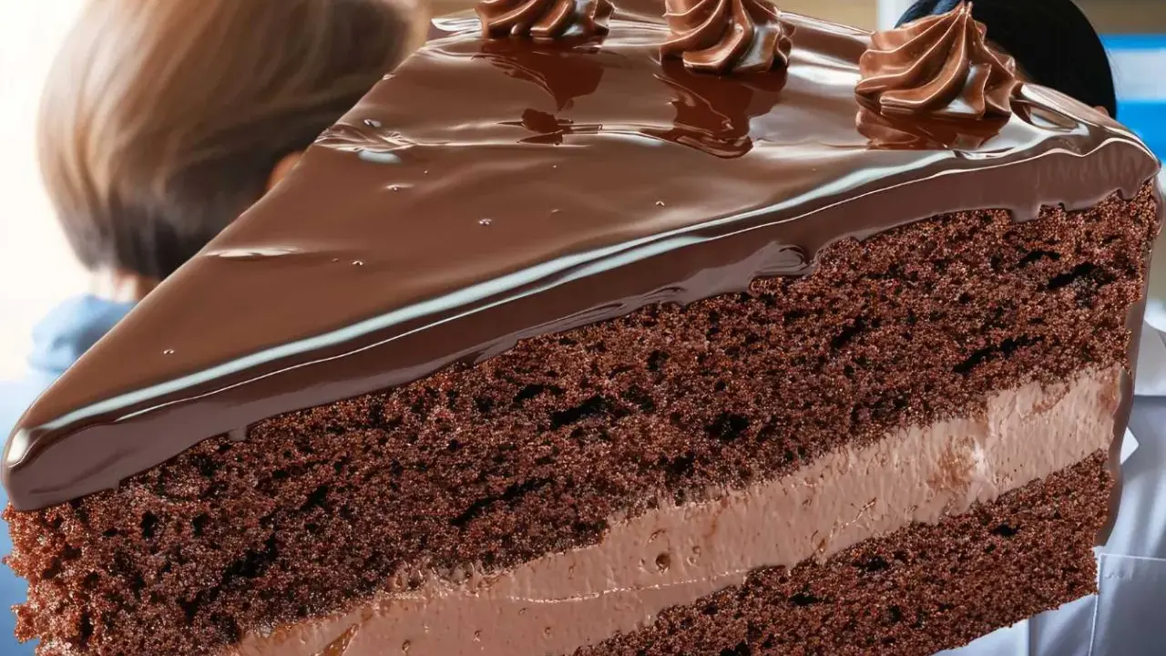 Une part généreuse de gâteau au chocolat, nappée de glaçage brillant et décorée de volutes de crème. Un délice qui rappelle l'opulence d'un opéra gateau.