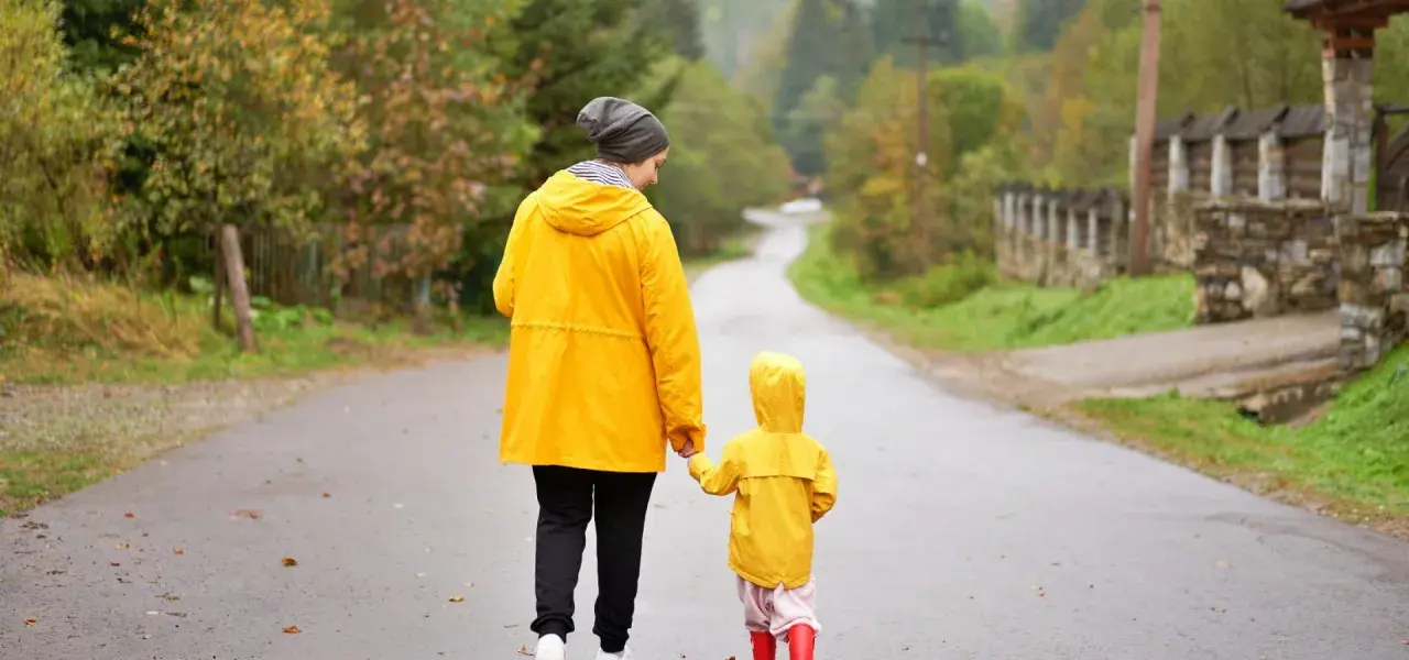 Mama i dziecko w żółtych płaszczach idą drogą. Nawet w deszczową pogodę Jastrzębia Góra oferuje atrakcje na niepogodę, jak wspólne spacery.
