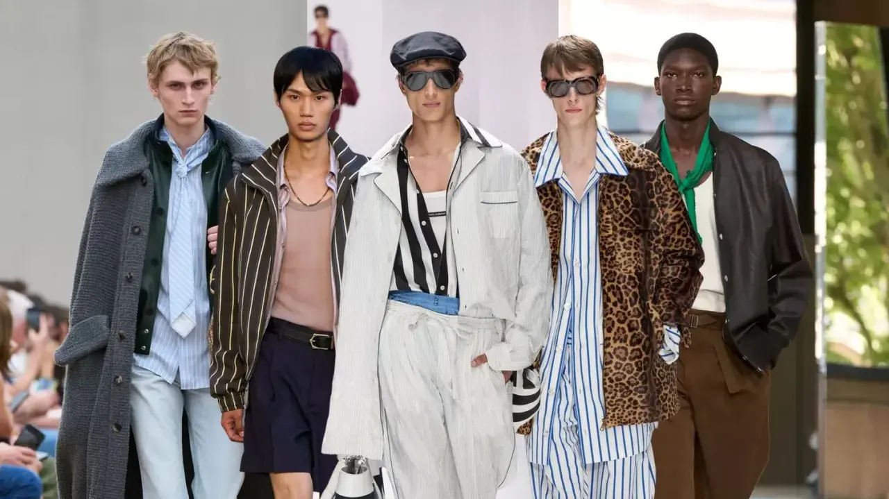 Five models showcase bold gay men fashion on a runway, featuring a mix of stripes, leopard print, and stylish outerwear.