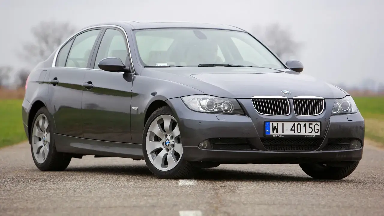 Szary sedan BMW E90 2.0 benzyna na drodze.