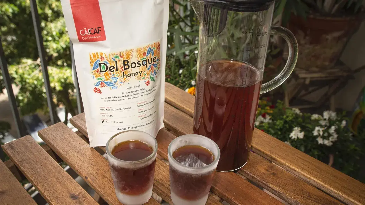 Kalter Kaffee in Gläsern auf Holztisch. Daneben eine Karaffe mit Kaffee und eine Packung "Del Bosque honey". Ein kühler Genuss an einem warmen Tag.