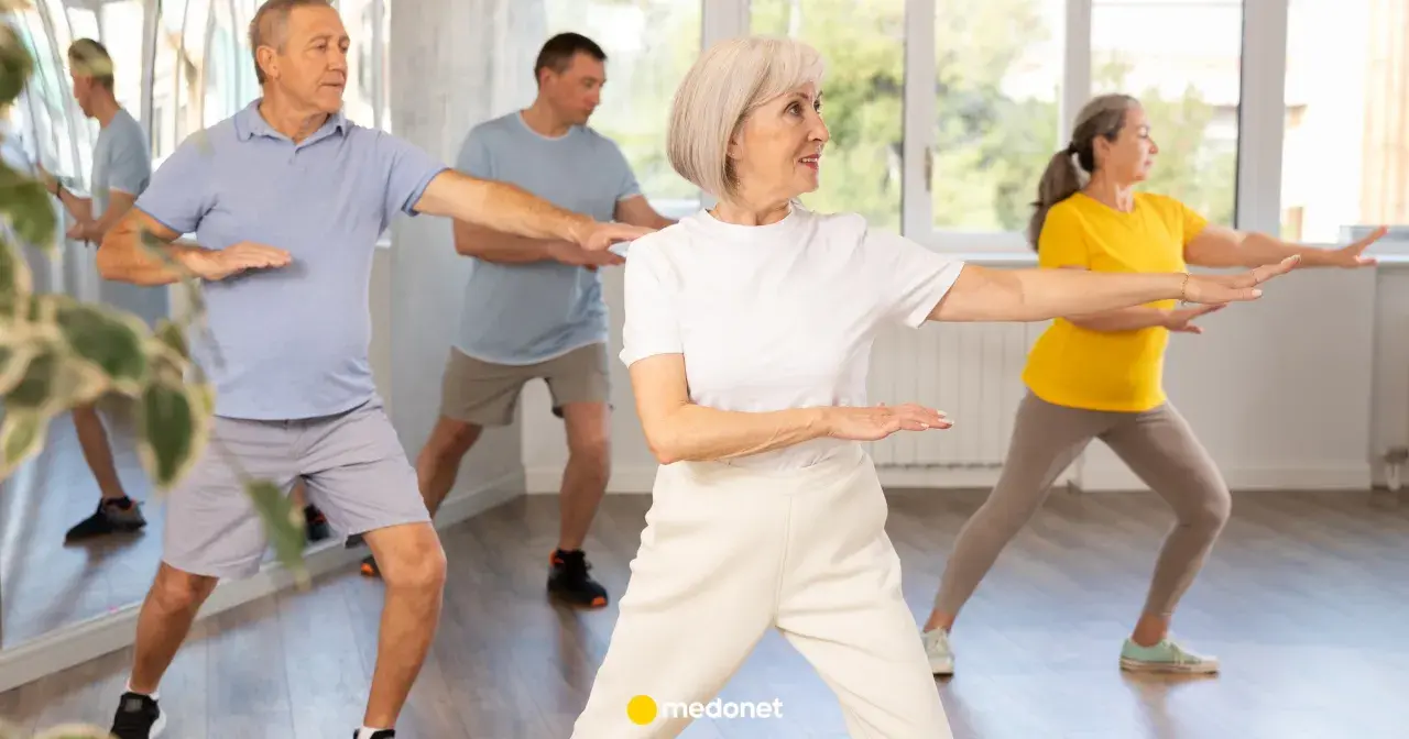 Seniorzy ćwiczą tai chi na krześle, poprawiając równowagę i spokój.