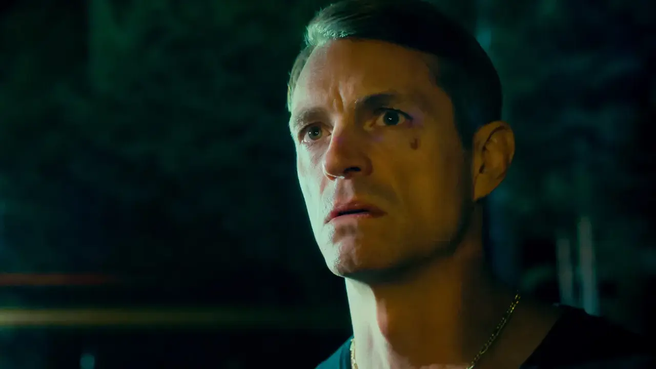 Joel Kinnaman i en mörk, intensiv scen från sin nya serie. Hans blick är fäst på något utanför bild, full av oro och beslutsamhet.