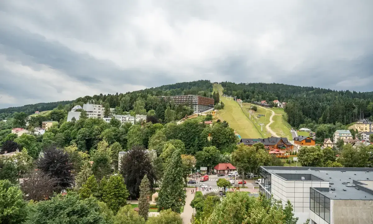 Widok na Krynicę-Zdrój z trasą narciarską i zabudowaniami. Sprawdź sanatorium krynica zdrój cennik.