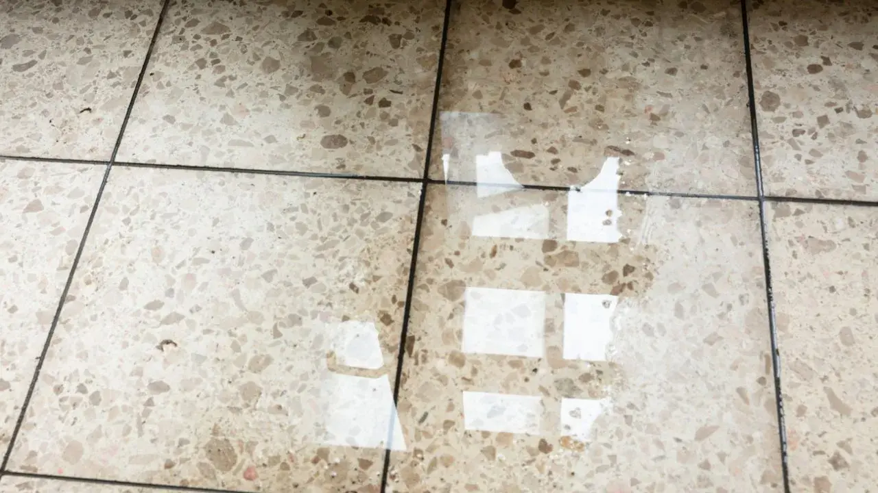 Eau sur le sol d'une maison, reflétant la lumière. L'isolation du sol est compromise.