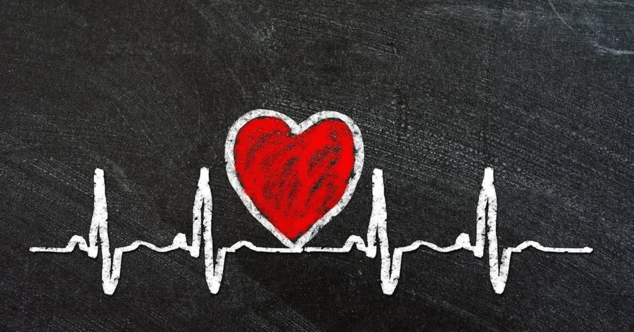 Czerwone serce na tle EKG symbolizuje zagrożenia dla zdrowia serca, w tym skutki otyłości u mężczyzn.