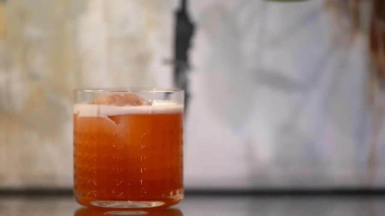 Ein erfrischender Jungle Bird Cocktail mit Eis und Schaum in einem Glas mit Rautenmuster.